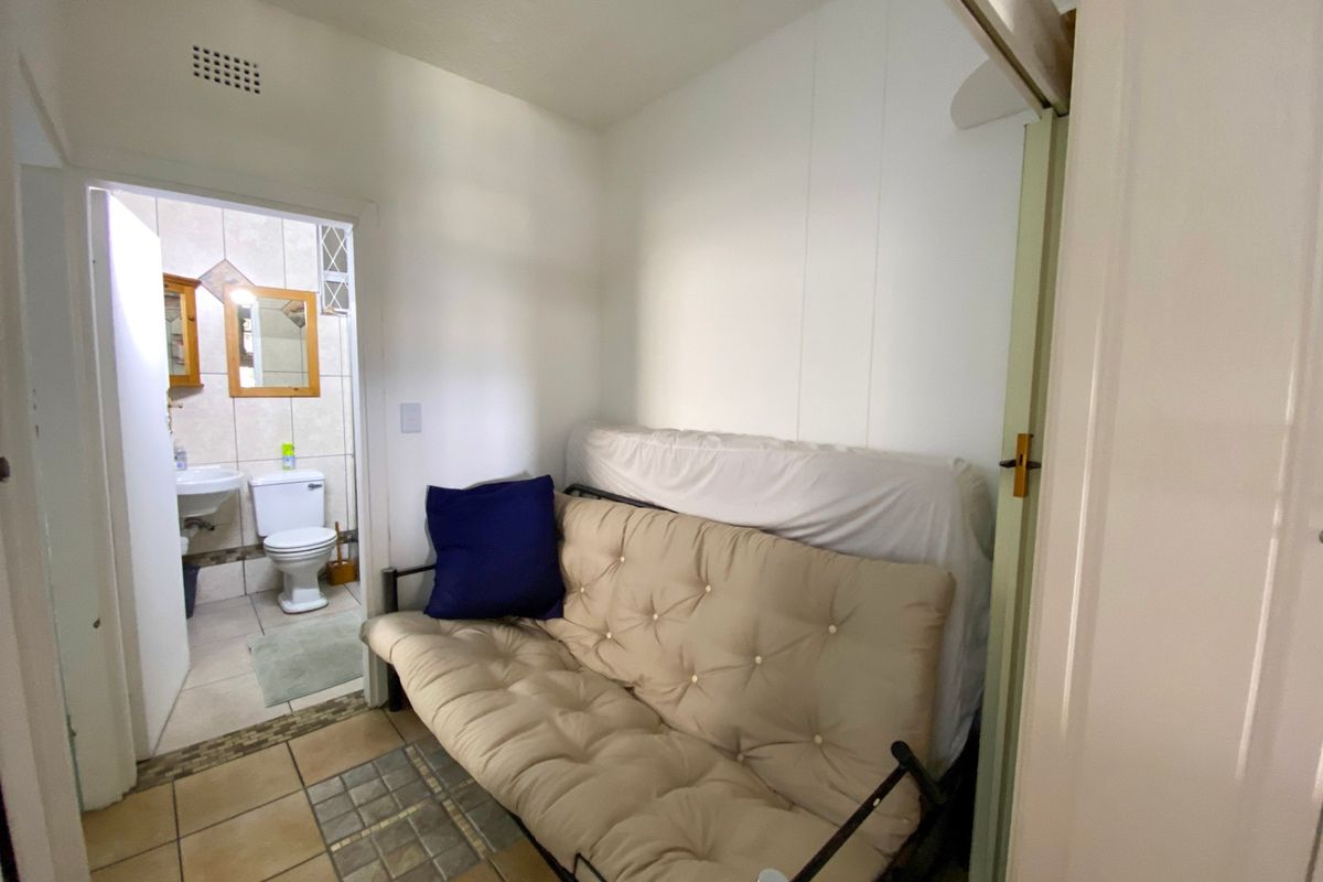 A compact bedroom area featuring tiled flooring and a ventilation grille, with direct access to an adjoining bathroom.