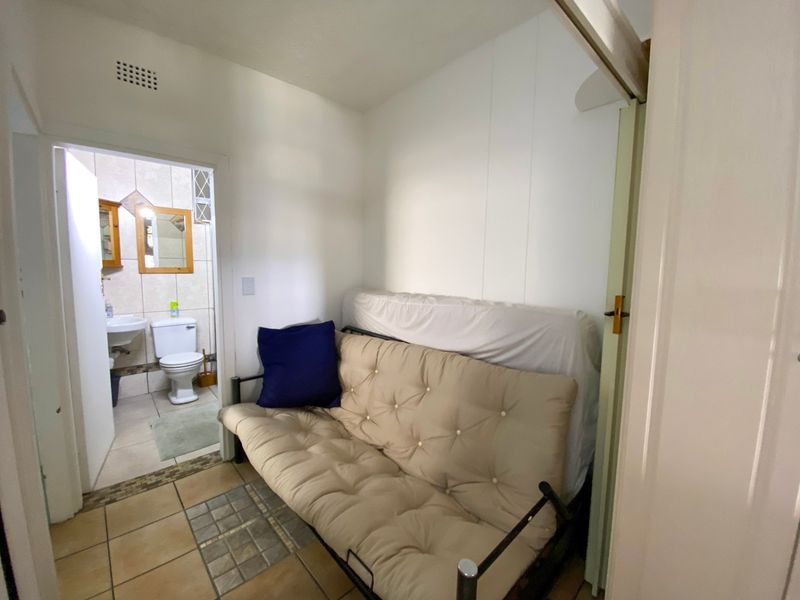 A compact bedroom area featuring tiled flooring and a ventilation grille, with direct access to an adjoining bathroom.