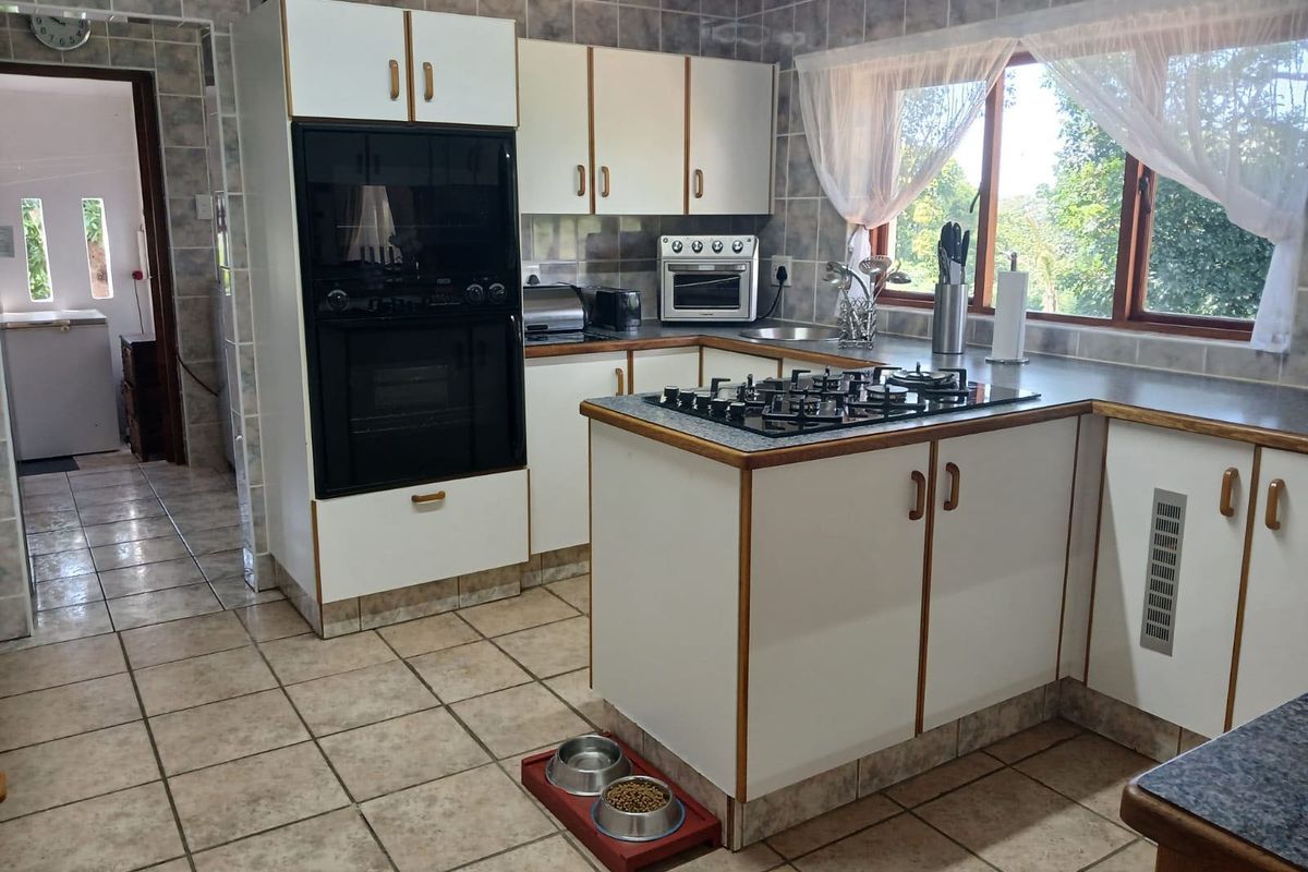 A functional kitchen featuring built-in cabinetry, a gas hob, a wall-mounted oven, and tiled finishes throughout, offering a classic layout with natural light.
