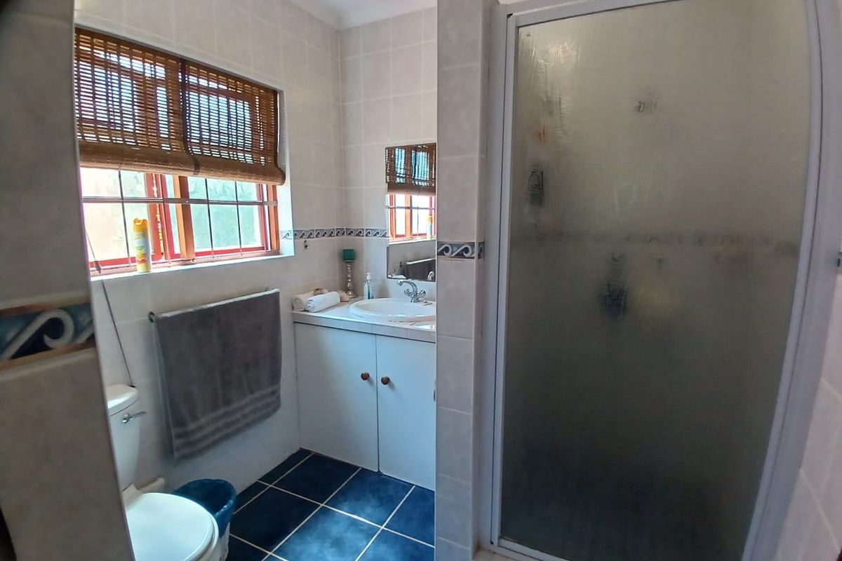 A functional bathroom featuring a shower enclosure, vanity cabinet with basin, and toilet, finished with tiled walls and flooring.