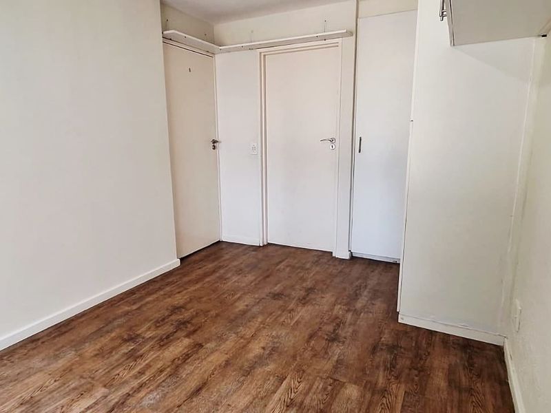 An empty bedroom featuring laminate flooring and built-in cupboard storage, offering a clean and neutral space ready for personalization.