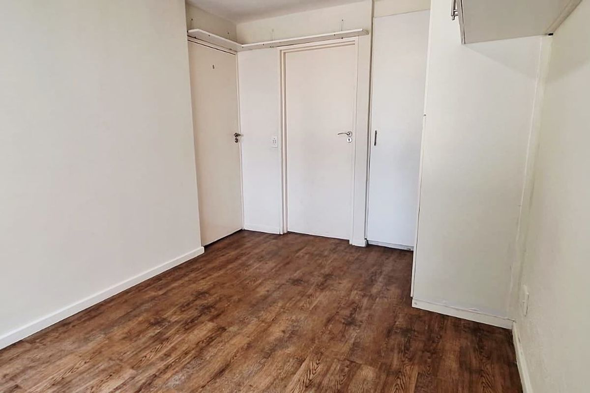 An empty bedroom featuring laminate flooring and built-in cupboard storage, offering a clean and neutral space ready for personalization.