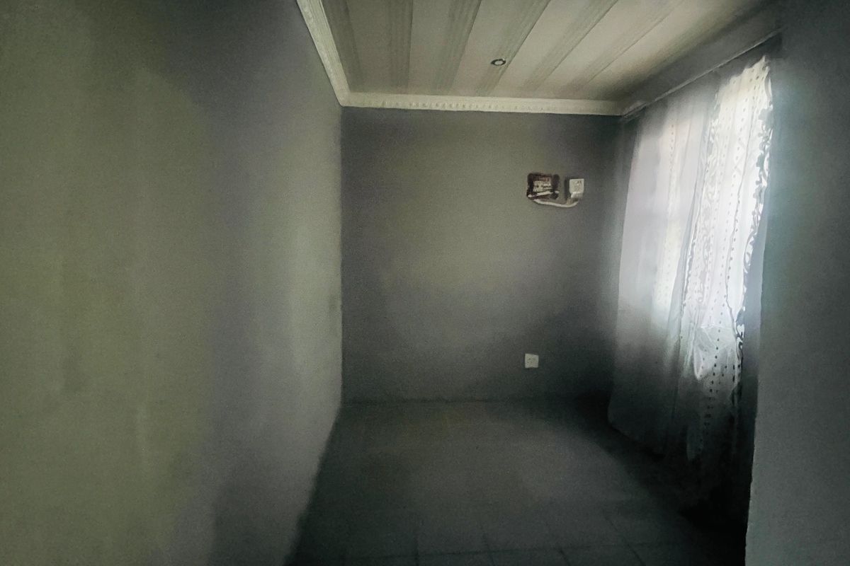 An empty bedroom featuring unfinished wall surfaces, ceiling cornicing, and exposed electrical wiring, requiring cosmetic updates and finishing touches.