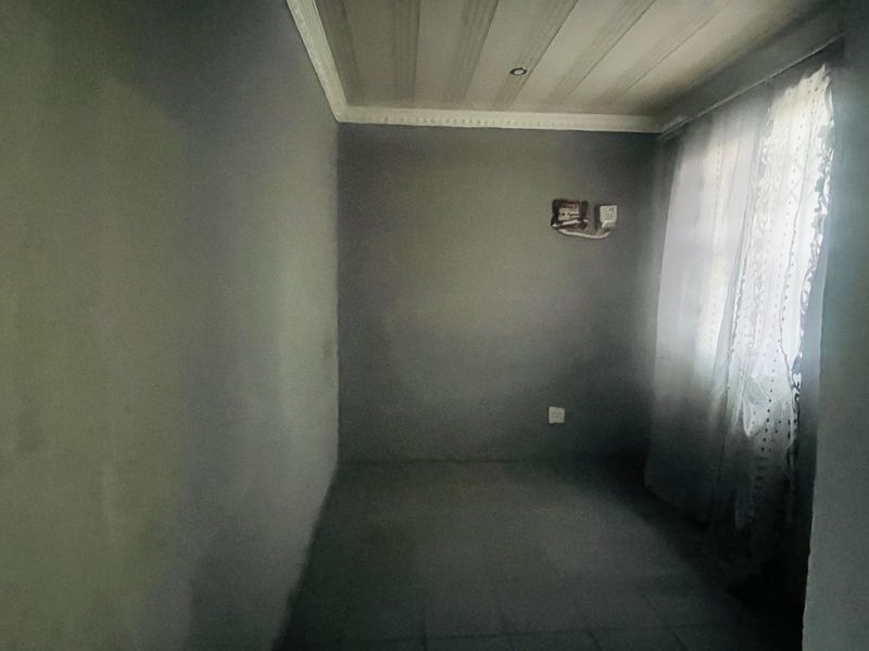 An empty bedroom featuring unfinished wall surfaces, ceiling cornicing, and exposed electrical wiring, requiring cosmetic updates and finishing touches.