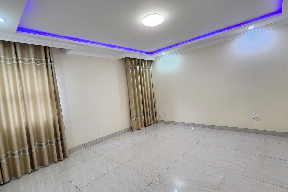 A bright, empty bedroom featuring modern recessed ceiling lighting, decorative LED strip accents, and neutral tiled flooring throughout.