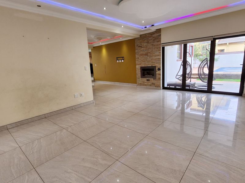 Spacious living area featuring polished porcelain tiles, a stone-clad fireplace, and sliding glass doors leading to the outdoor patio area.