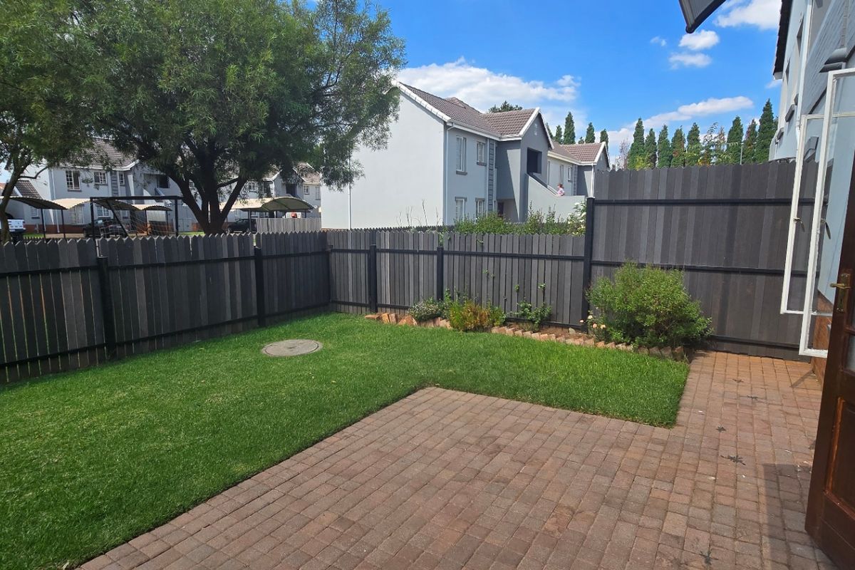 A private rear garden featuring a paved patio area, a well-maintained lawn, and secure timber fencing.
