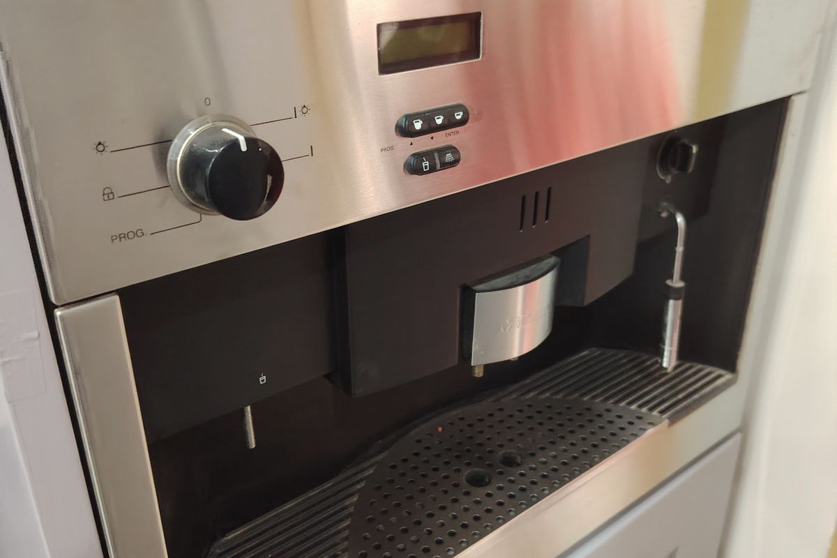 A close-up view of a built-in Miele coffee machine integrated into modern kitchen cabinetry.