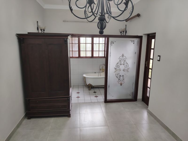 A bathroom featuring a classic clawfoot bathtub, tiled flooring, and a decorative frosted glass sliding door, providing a unique layout.