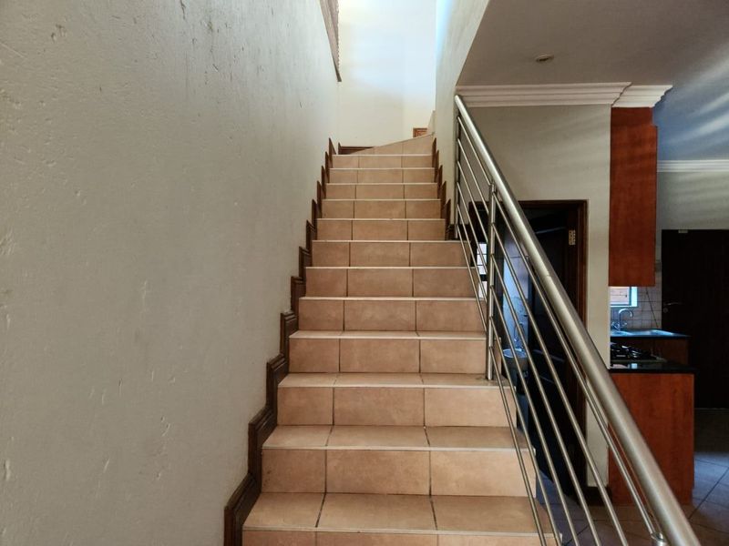 A staircase featuring tiled steps and a modern stainless steel balustrade, leading to the upper level of the home.