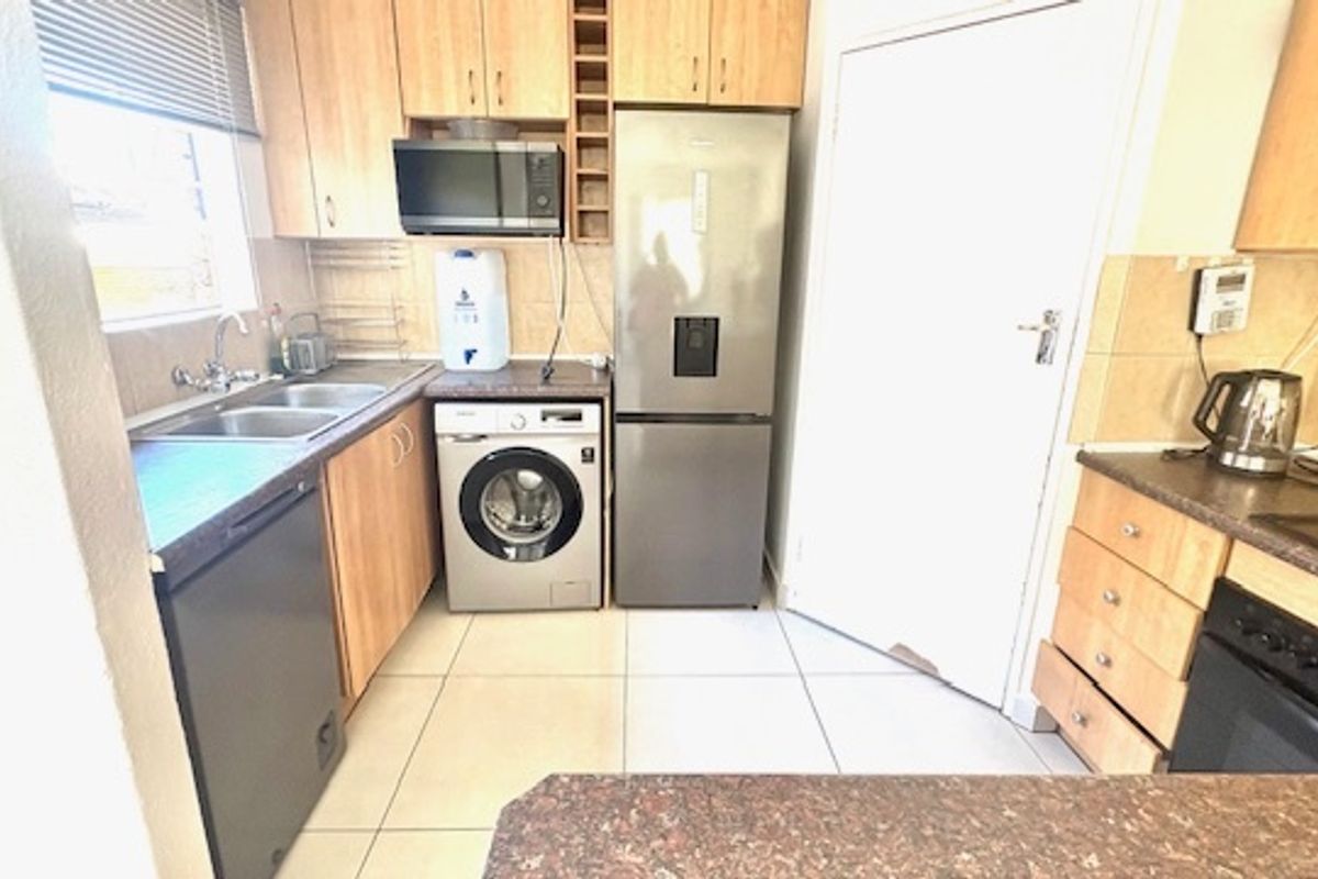 Functional kitchen featuring light wood cabinetry, tiled flooring, built-in oven and hob, and integrated appliance spaces.