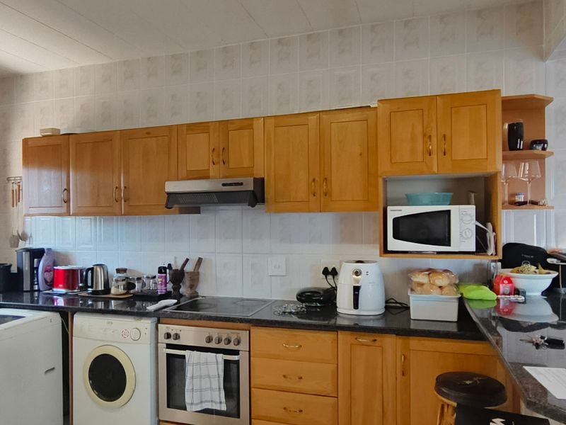 A functional kitchen featuring wooden cabinetry, granite countertops, a built-in oven with hob, and a breakfast bar, providing ample workspace and storage.