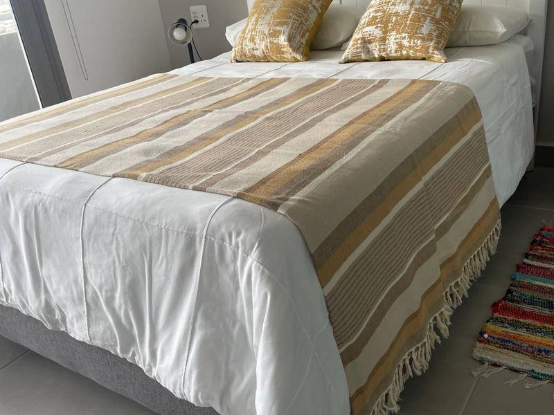 A well-maintained bedroom featuring neutral tiled flooring and access to an outdoor area via a sliding door.