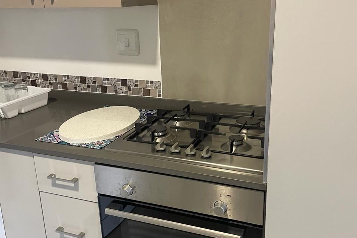A modern kitchen area featuring a built-in Bosch oven, gas hob, stone countertops, and clean, contemporary cabinetry with a tiled backsplash.