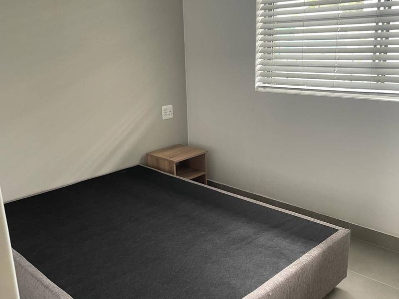 A neutral bedroom featuring tiled flooring, clean wall finishes, and venetian blinds, providing a simple and functional space.