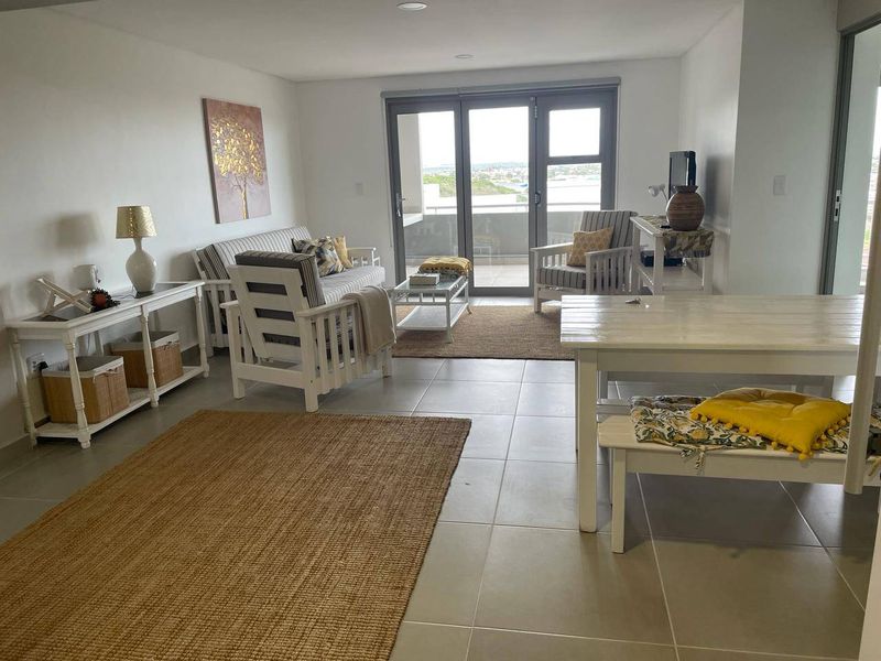 Bright and spacious living area featuring neutral tiled flooring, recessed lighting, and large sliding glass doors providing access to the balcony.
