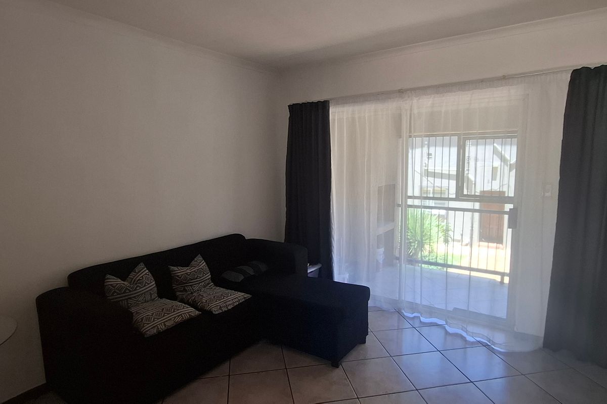 A living room featuring tiled flooring and a large sliding glass door providing access to an outdoor area.