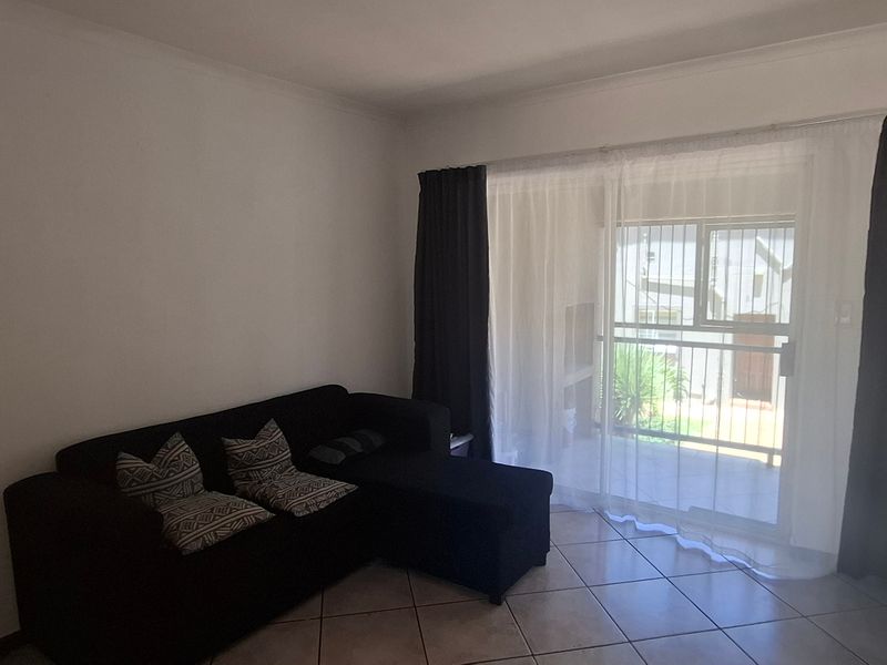 A living room featuring tiled flooring and a large sliding glass door providing access to an outdoor area.