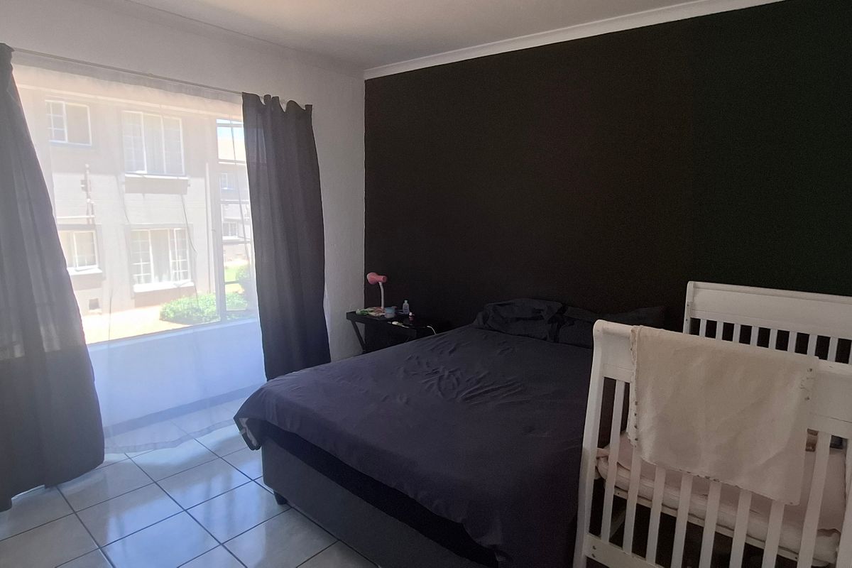 A bedroom featuring tiled flooring and a dark accent wall, providing a neutral base for potential interior design updates.