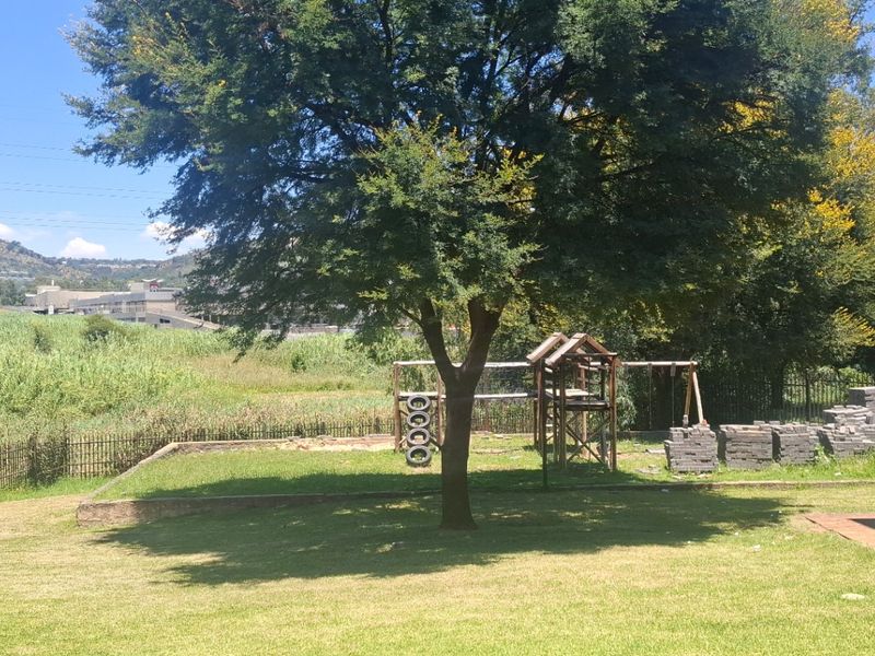 A spacious rear garden area featuring a well-maintained lawn, mature tree, and perimeter fencing with views of the surrounding landscape.
