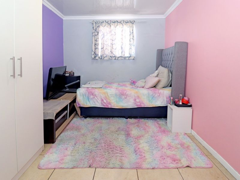A bedroom featuring tiled flooring, built-in wardrobe cabinetry, and a window with curtain fixtures.