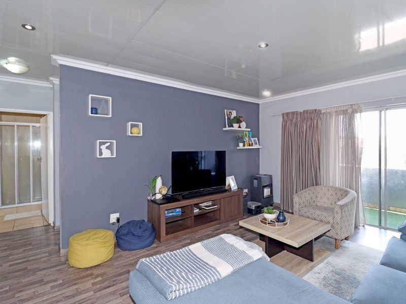 Open plan living area featuring a grey accent wall, recessed downlighting, and sliding glass doors leading to a private balcony.