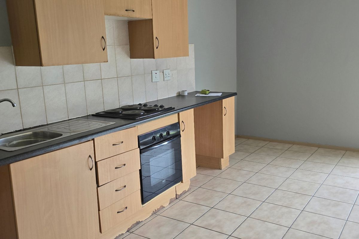 A functional kitchen featuring laminate cabinetry, a built-in oven, electric hob, and tiled flooring, offering a blank canvas for potential updates.