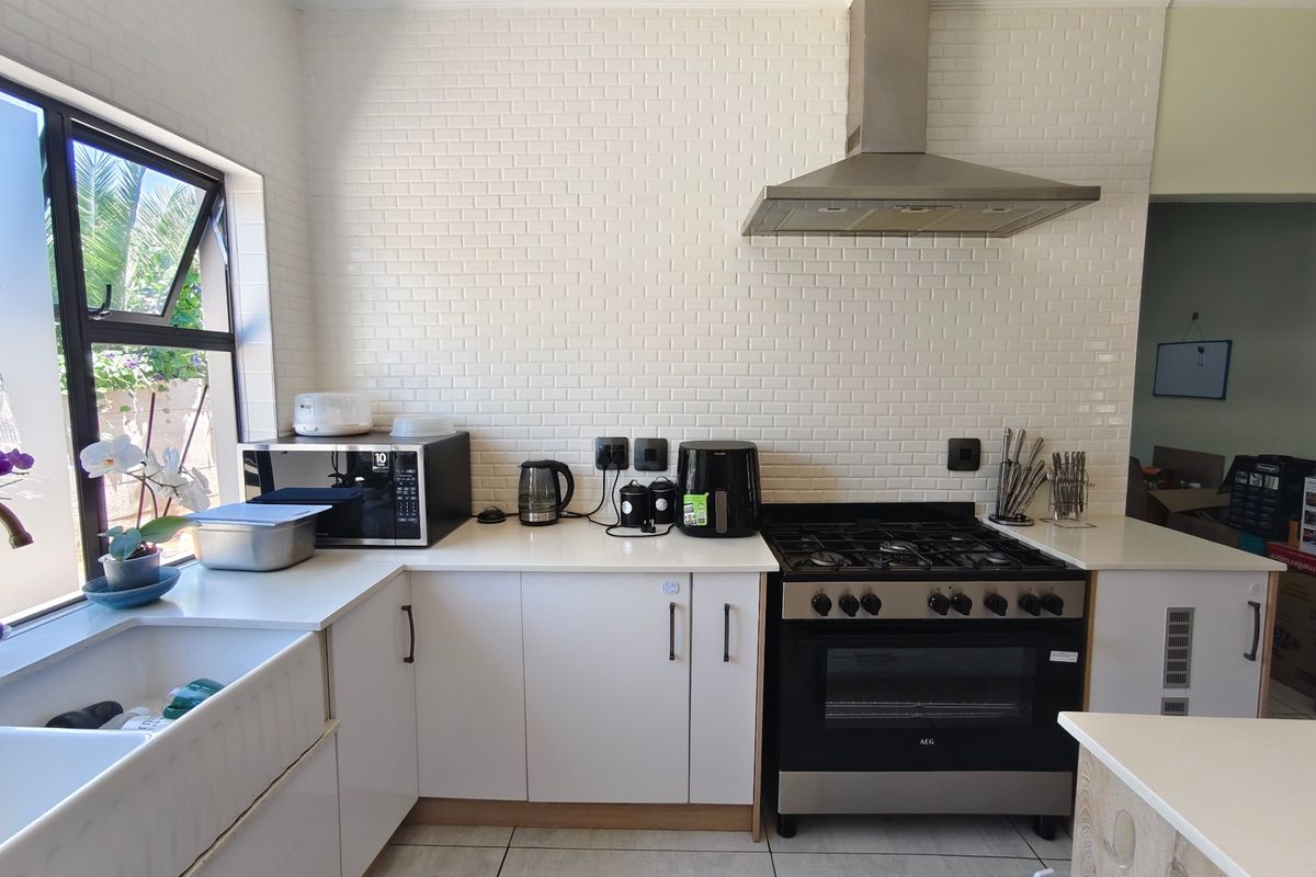 Modern kitchen featuring white subway tile backsplash, quartz countertops, apron front sink, and stainless steel gas oven with extractor fan.