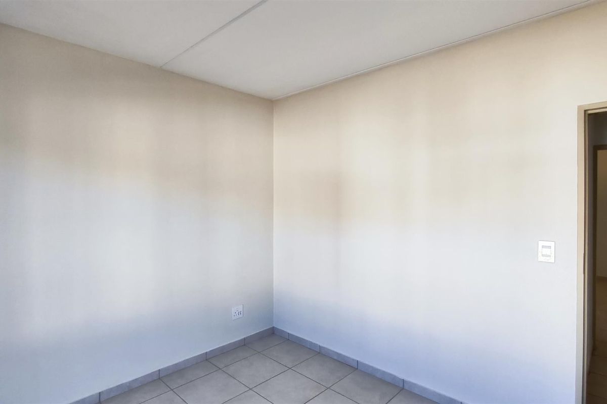 A clean, empty bedroom featuring neutral wall finishes and tiled flooring, providing a versatile blank canvas for personalization.