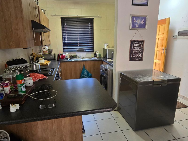 Functional kitchen featuring laminate cabinetry, tiled backsplash, and a breakfast nook counter, providing a practical workspace with integrated hob and extractor fan.