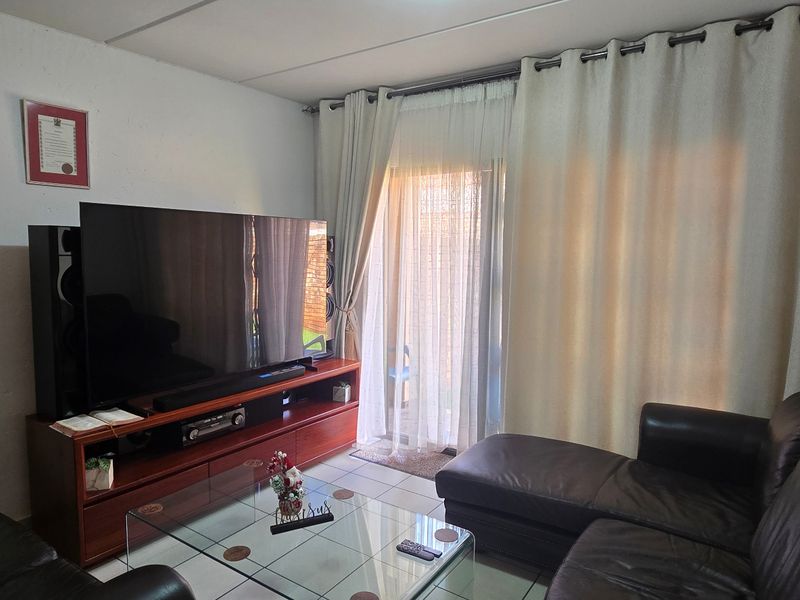 A comfortable living room featuring tiled flooring and a sliding glass door that provides access to the outdoor area.