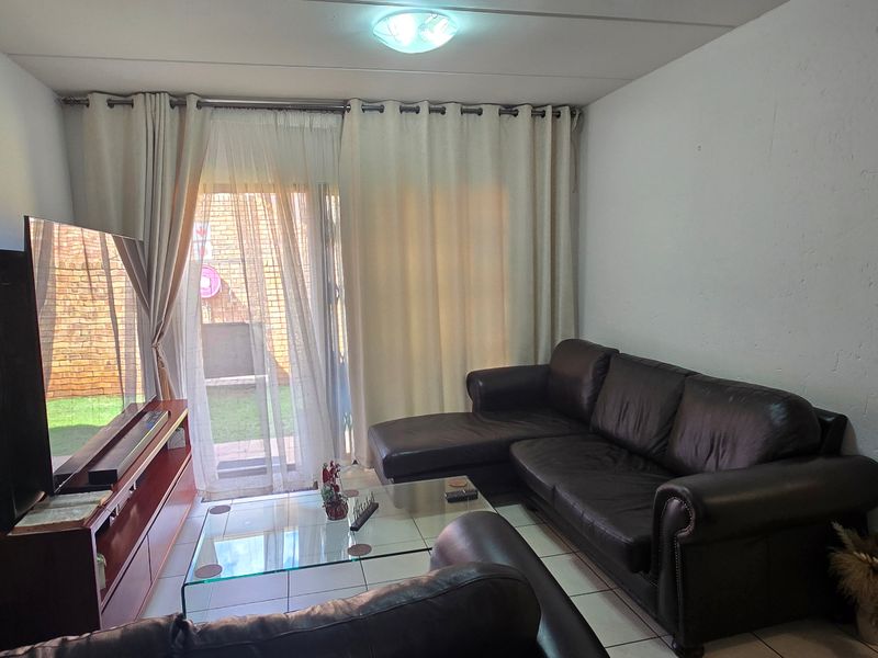 A comfortable living room featuring tiled flooring and a sliding glass door that provides access to the outdoor area.