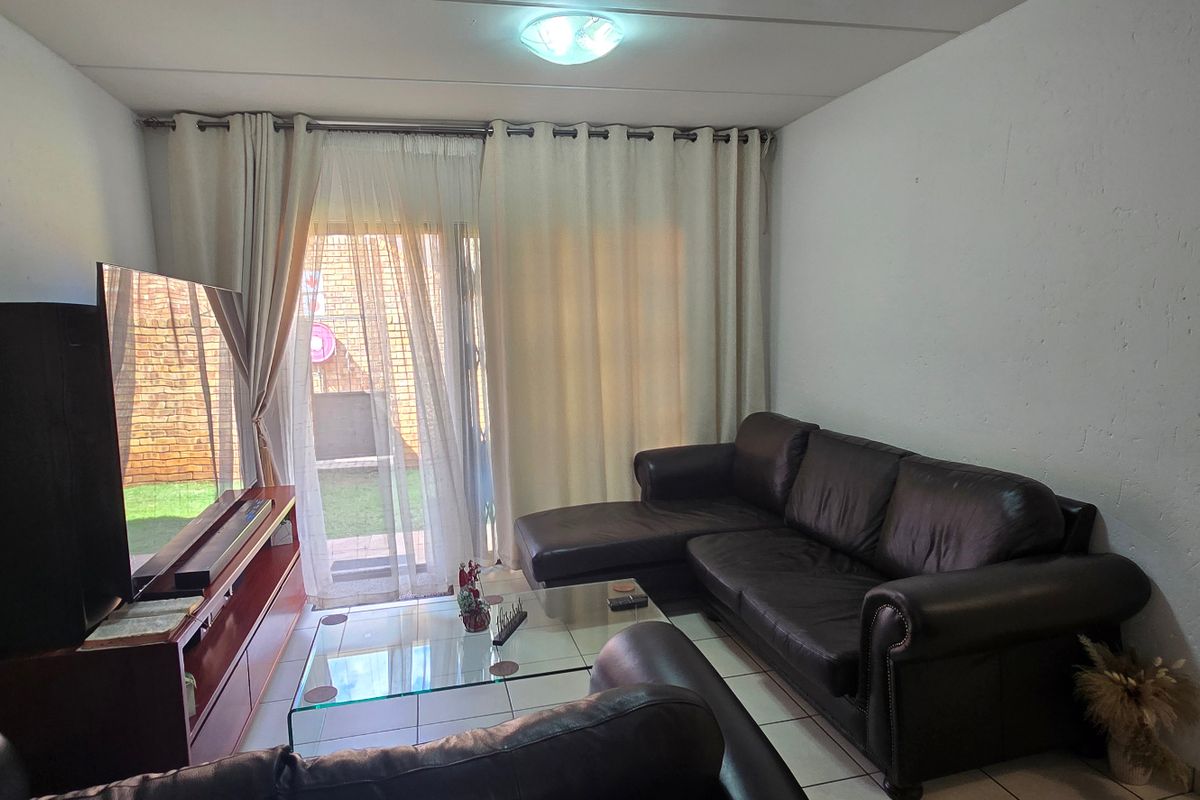 A comfortable living room featuring tiled flooring and a sliding glass door that provides access to the outdoor area.