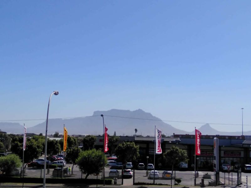 A clear view of the mountain range overlooking a commercial shopping center and parking area.
