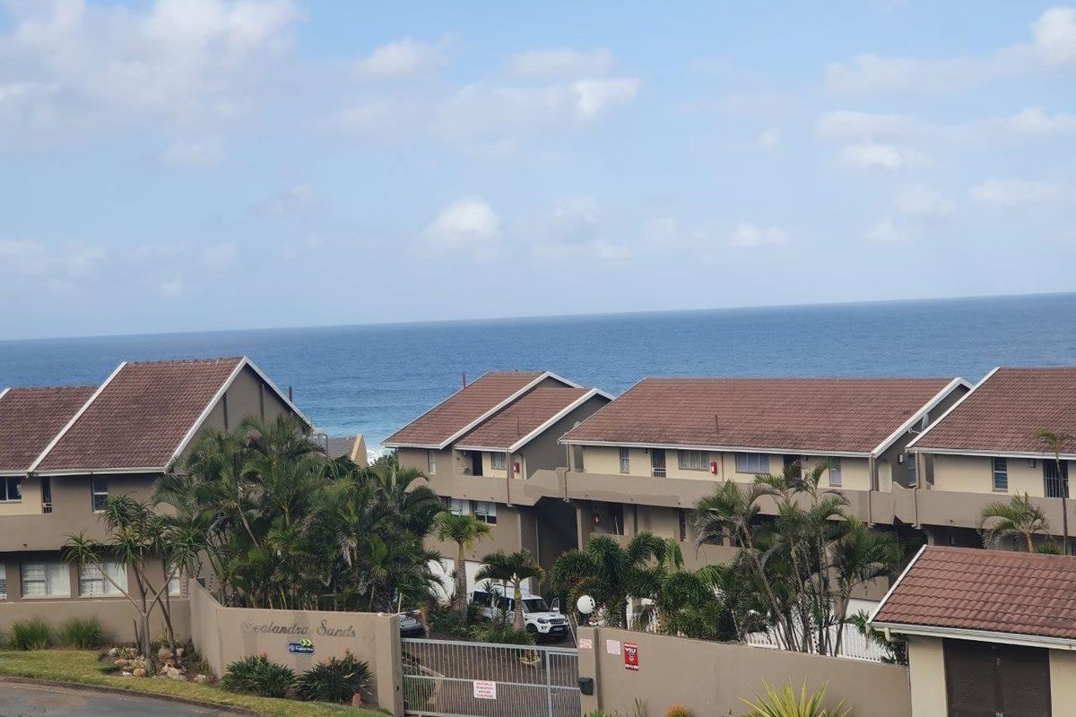 An elevated view of the Sealandra Sands commercial complex, featuring tiled roofing, perimeter security walls, and ocean views.