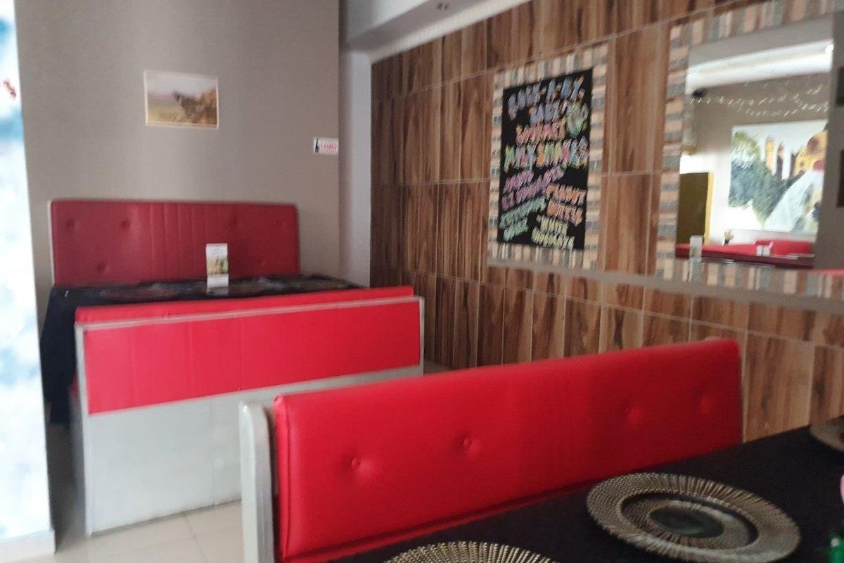 Commercial dining area featuring built-in red booth seating, wood-look wall paneling, and tiled flooring.