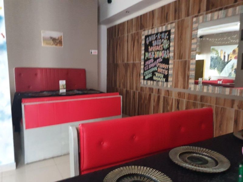 Commercial dining area featuring built-in red booth seating, wood-look wall paneling, and tiled flooring.