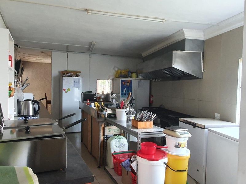 Commercial kitchen space featuring a stainless steel extractor hood, tiled splashbacks, and functional layout suitable for food preparation and service.