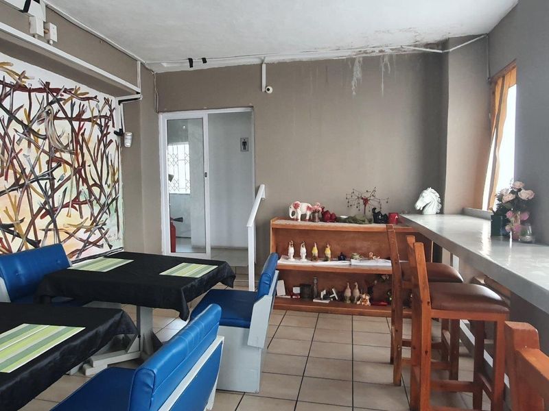 Commercial interior space featuring tiled flooring, a built-in counter, and access to a restroom, showing signs of ceiling water damage requiring maintenance.