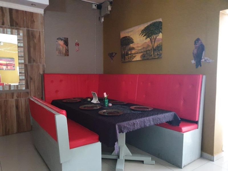A commercial dining area featuring built-in red booth seating and tiled flooring, suitable for restaurant or cafe use.