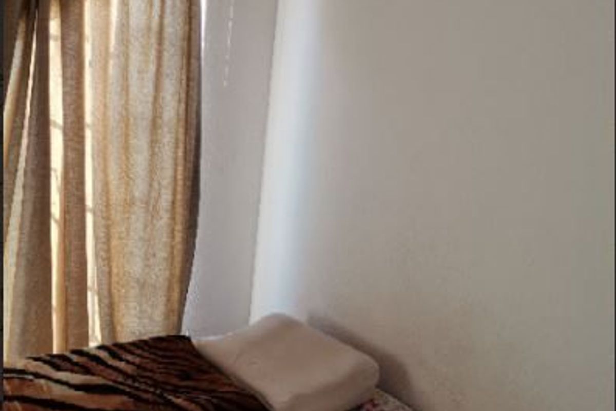 A bedroom corner featuring a window with installed curtain rails and neutral wall finishes.