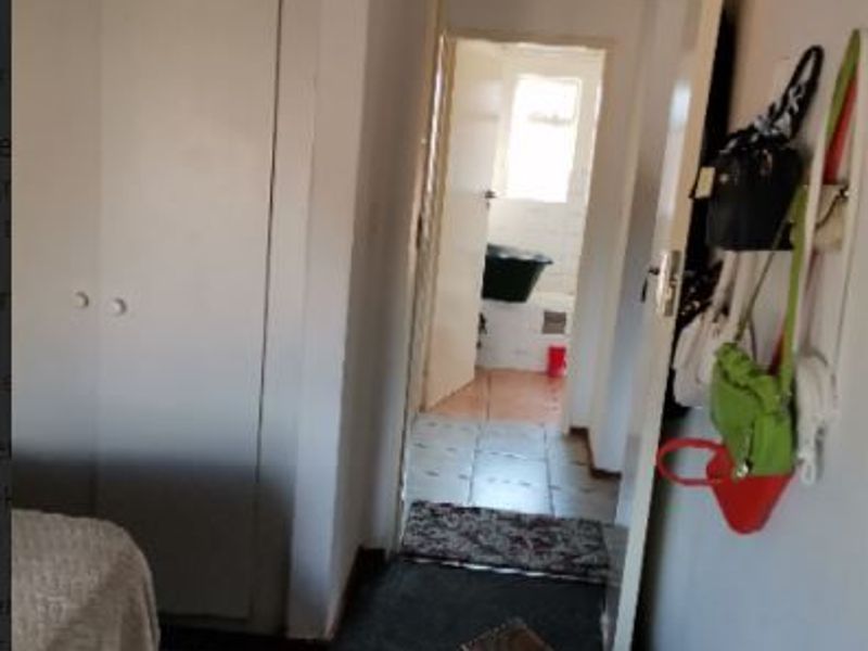 A functional hallway featuring built-in cupboards and tiled flooring, providing access to an adjacent bathroom area.