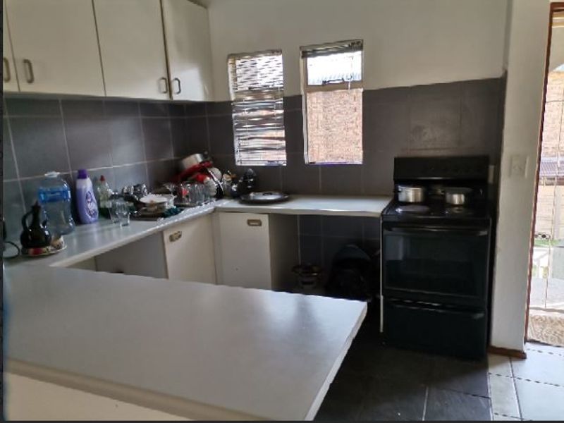A functional kitchen featuring built-in cabinetry, a tiled backsplash, a breakfast bar, and a freestanding stove, offering potential for modern updates.