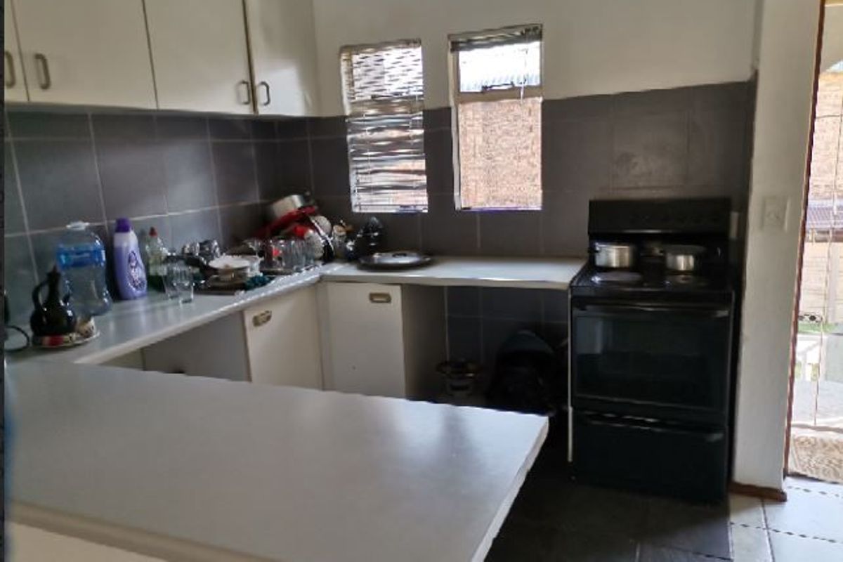 A functional kitchen featuring built-in cabinetry, a tiled backsplash, a breakfast bar, and a freestanding stove, offering potential for modern updates.