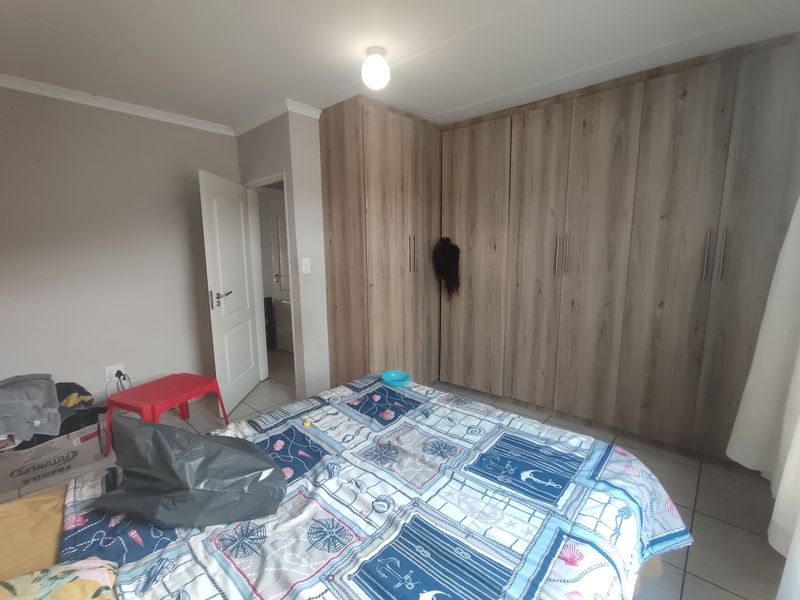 A bedroom featuring light wood-finish built-in cupboards and tiled flooring.