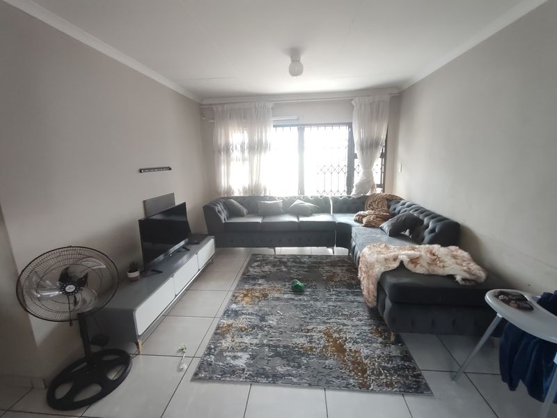 A functional living room featuring tiled flooring and a window fitted with a security gate, providing a neutral base for interior updates.