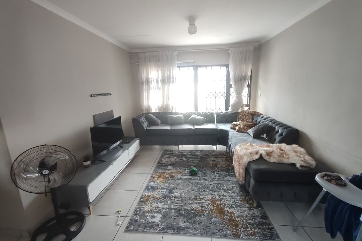 A functional living room featuring tiled flooring and a window fitted with a security gate, providing a neutral base for interior updates.