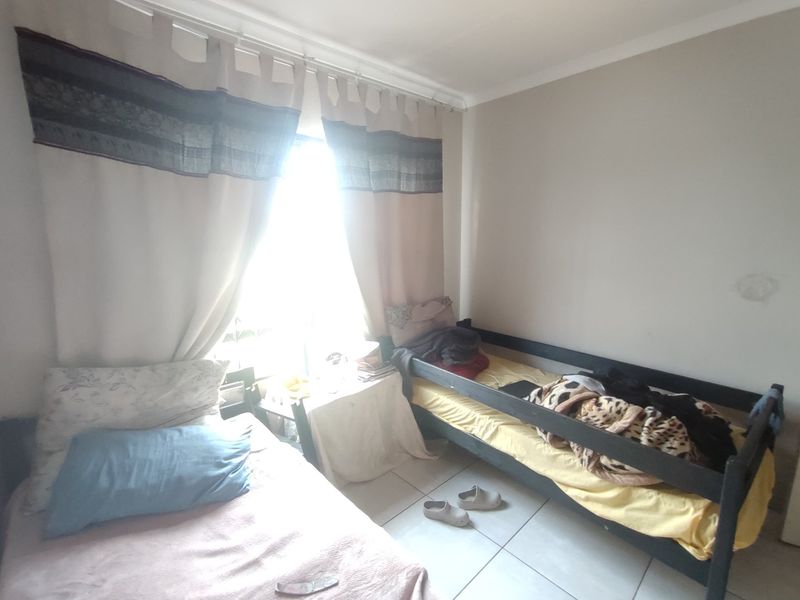 A bedroom featuring tiled flooring and natural light, currently utilized as a shared sleeping space.