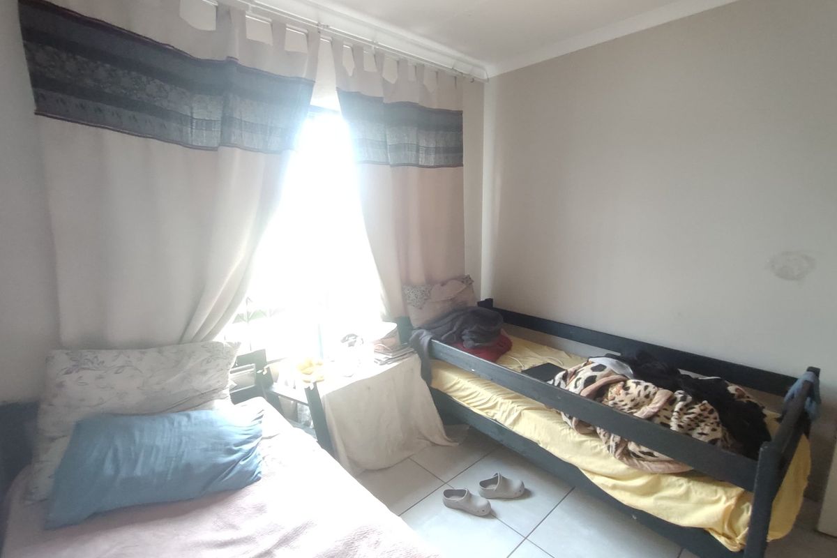 A bedroom featuring tiled flooring and natural light, currently utilized as a shared sleeping space.