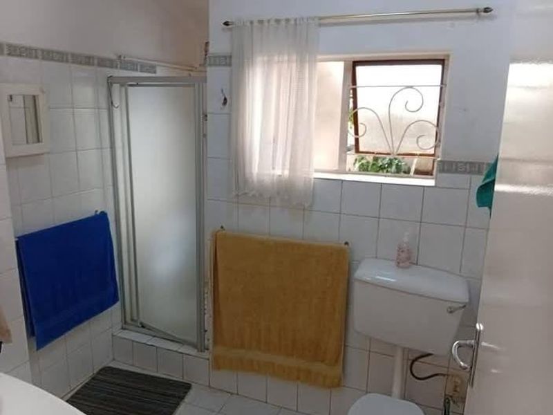 A functional bathroom featuring a shower enclosure, toilet, and tiled finishes. The space would benefit from modern updates to fixtures and finishes.